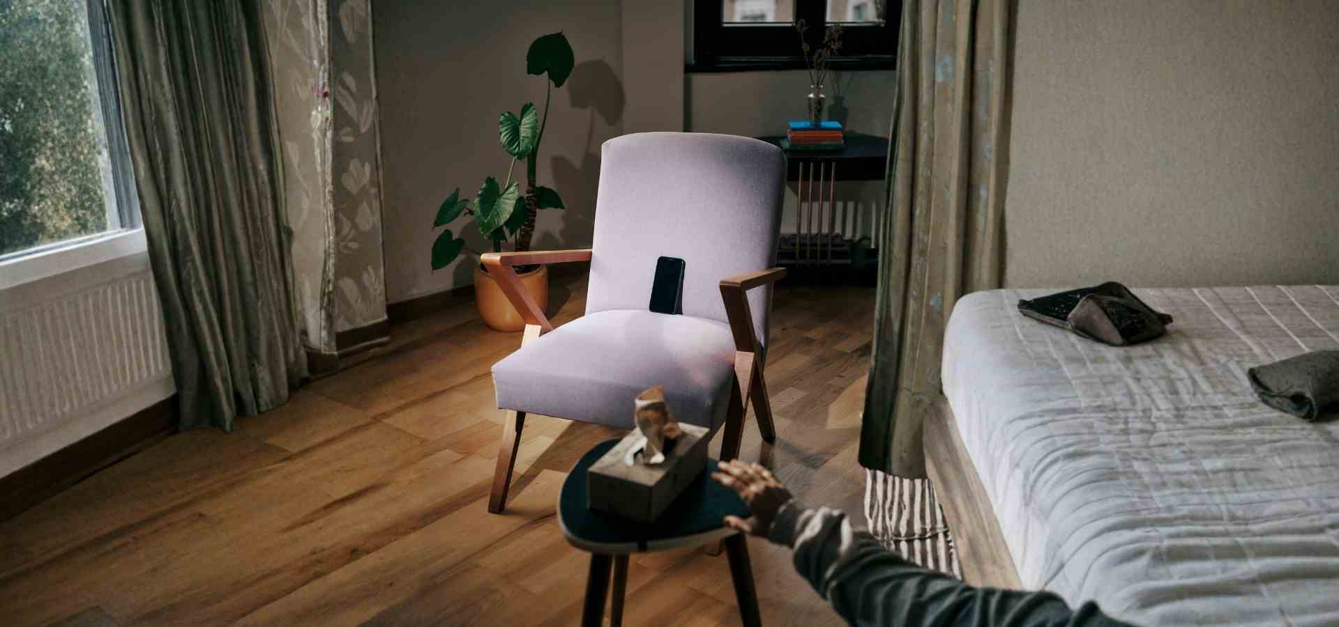 Leerer Therapiesessel mit Smartphone – Wartelisten und KI als Therapieersatz Leerer Sessel mit Smartphone auf der Armlehne und Taschentuchbox daneben, Person sitzt am Rand des Bettes – Symbolbild für den leeren Therapieplatz und das Warten auf psychologische Unterstützung