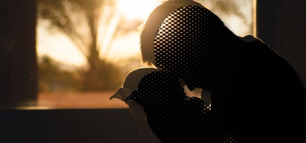 Person hält ein Baby im Gegenlicht vor einem Fenster, Symbolbild zu Depression bei Vätern nach der Geburt